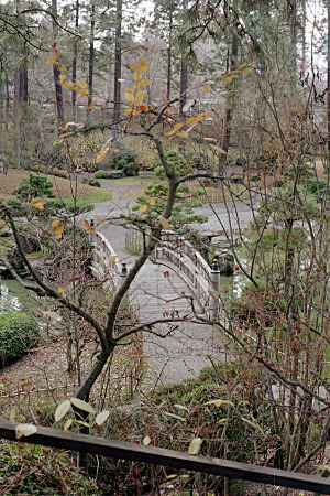 [A curved wooden bridge connects two parts of the walkway around the manicured grounds.]